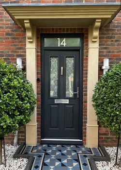 Stone effect door surround painted in Stonelux Buff 04 with a black door and trees on each side