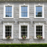 Dover 70 Windowsill Paint applied to exterior window surrounds on a grey stone building with a cool off-white stone finish