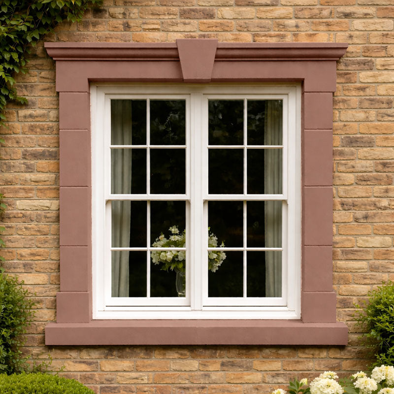 Millgate 37 Stonelux stone effect paint colour inspiration on an exterior window surround against yellow brick with a warm rose brown sandstone finish with muted pink and terracotta tones